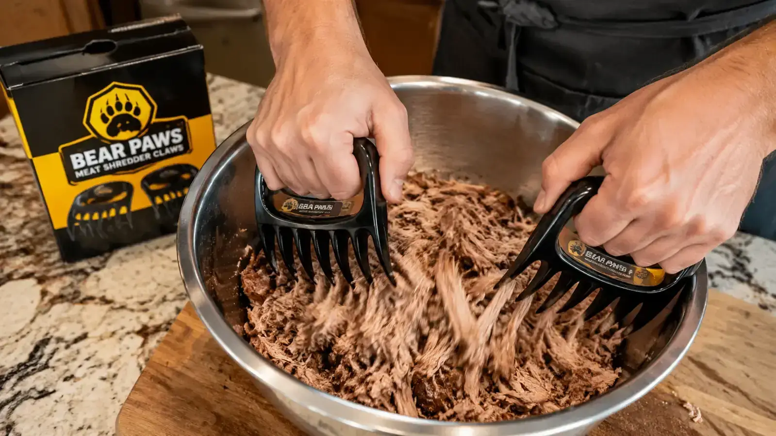 Hands wearing the Bear Paws claws shredding pulled pork directly in a stainless steel pan