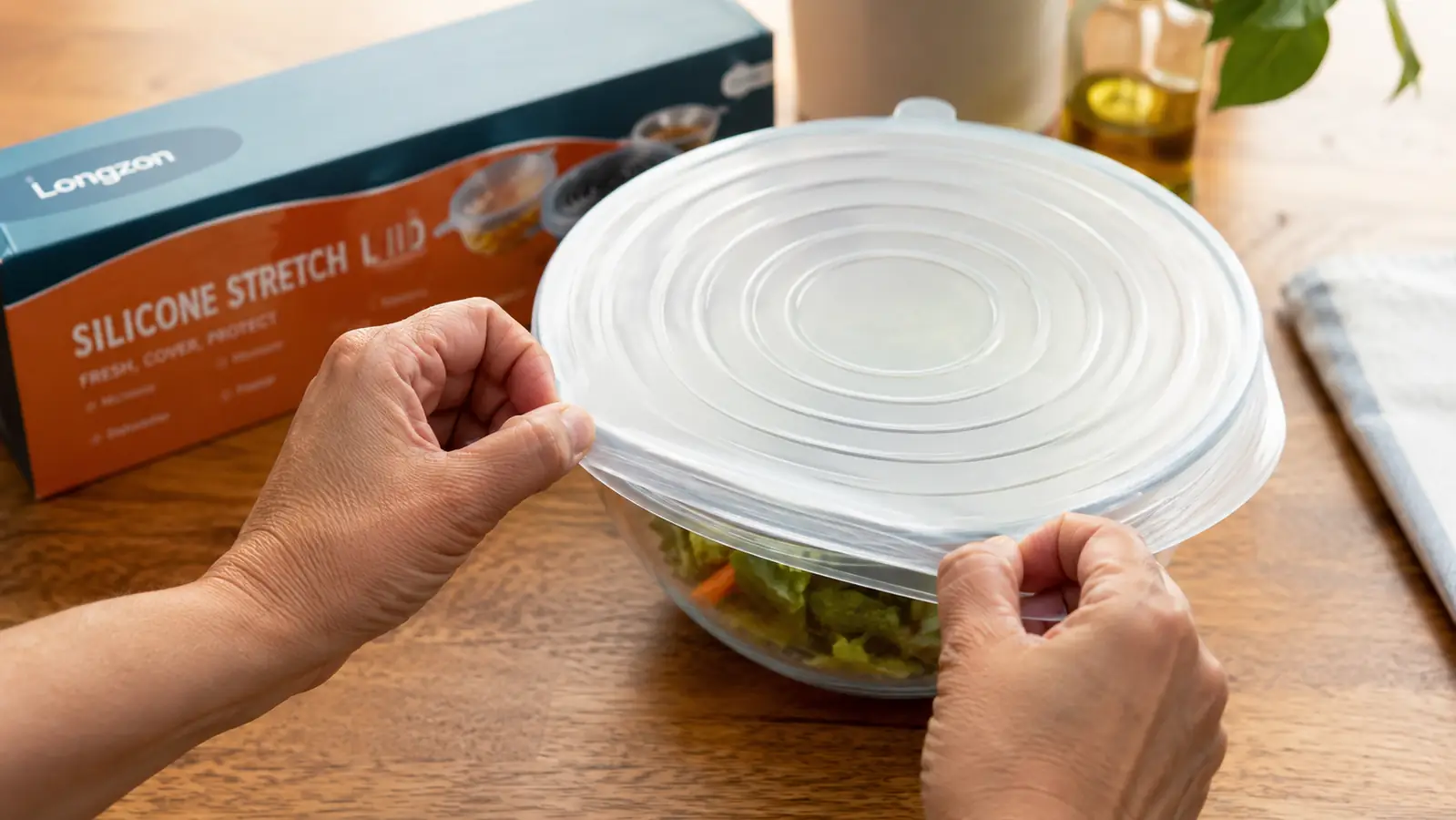 Close-up of hands stretching a Longzon silicone lid over the rim of a mixing bowl