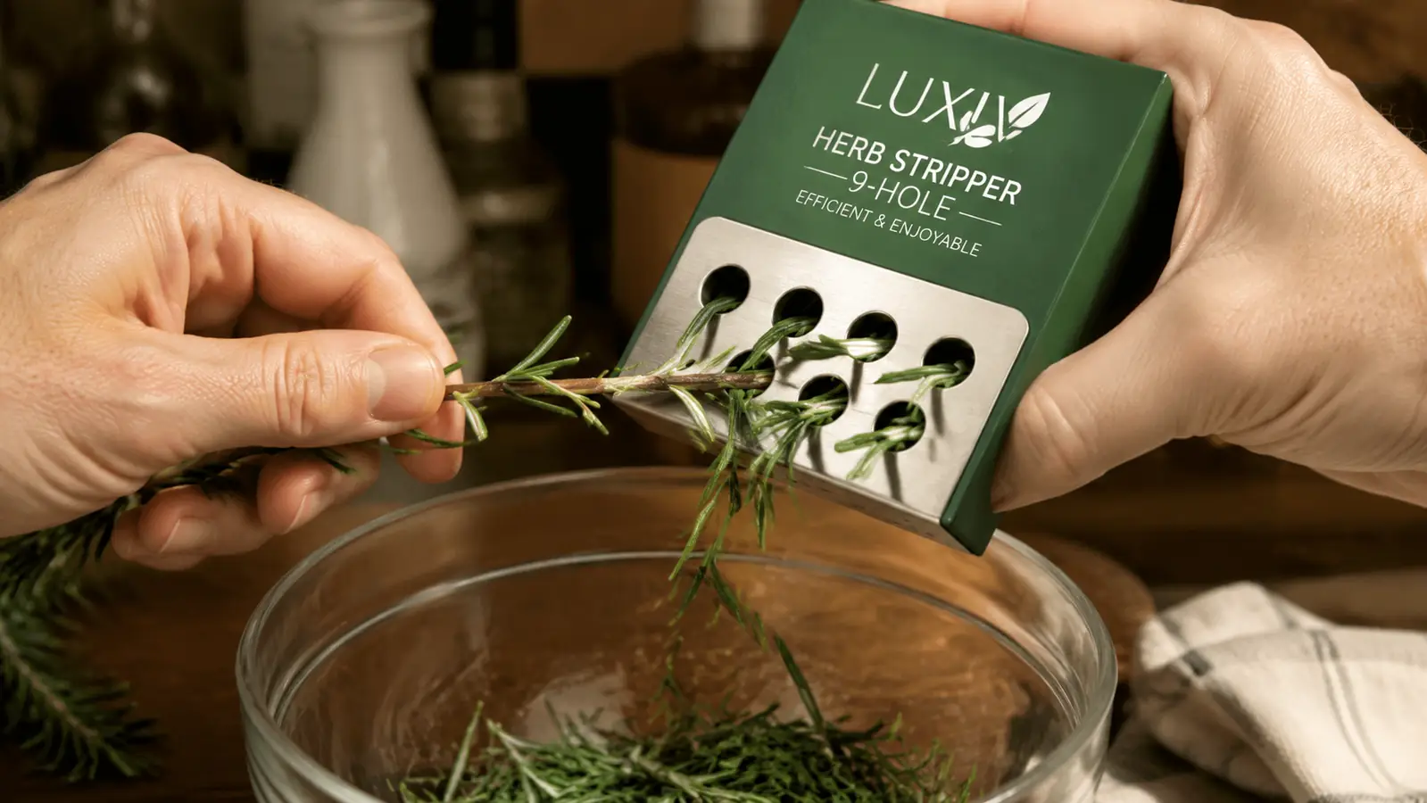 Hand pulling a rosemary stem through the Luxiv stainless steel herb stripper over a small glass bowl