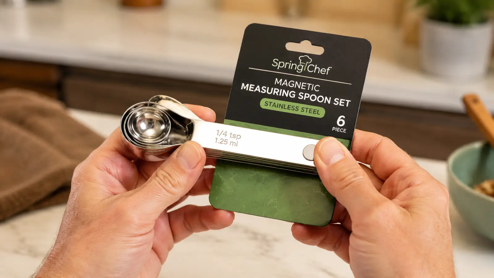 Hand holding a stack of Spring Chef magnetic measuring spoons snapped together at the handles
